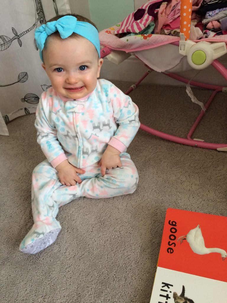 Smiling baby with bow and reading from adoption agency in Houston, TX